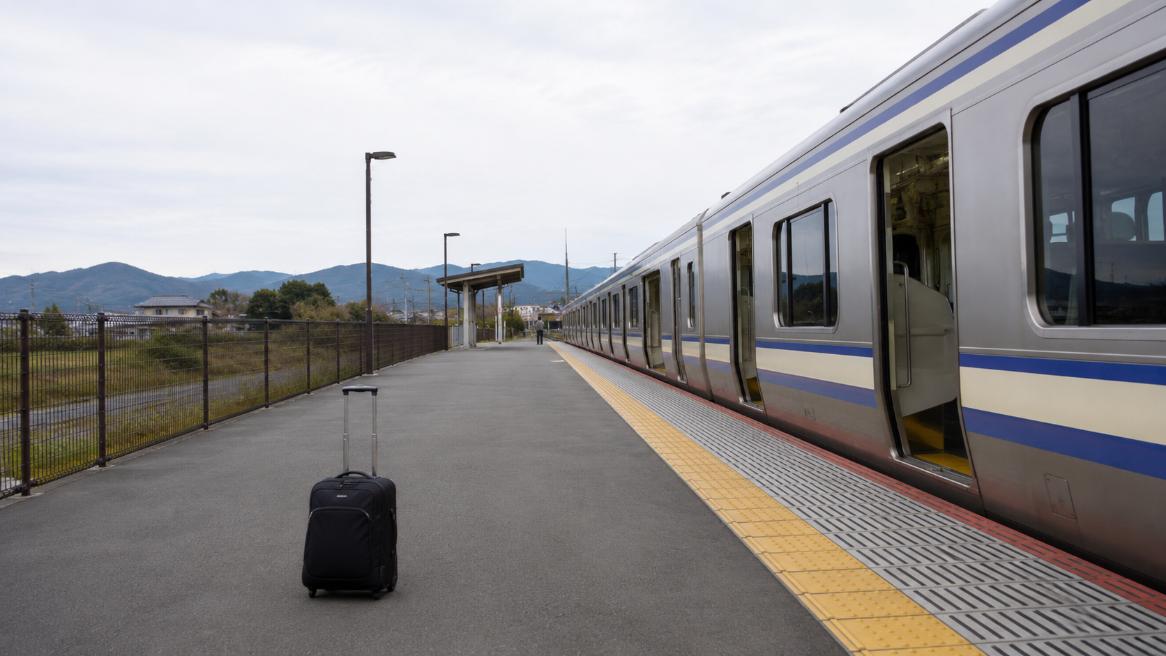 駅のホームに停まる電車とキャリーケースで公共交通旅行を表した写真