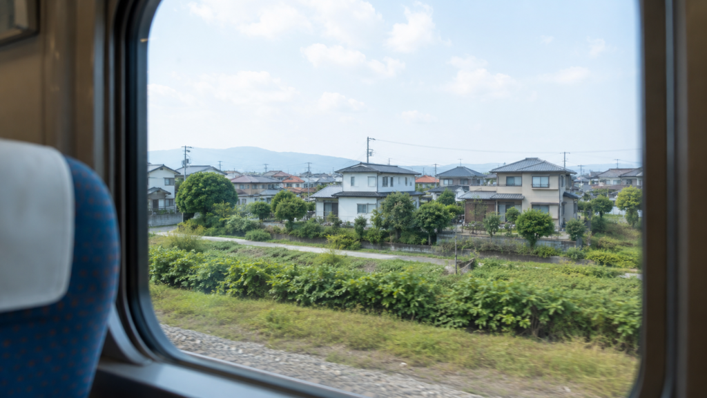 電車の車窓から見える穏やかな郊外の風景