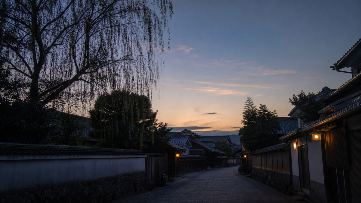 夕暮れの温泉街に柳並木と外湯の明かりがともる様子