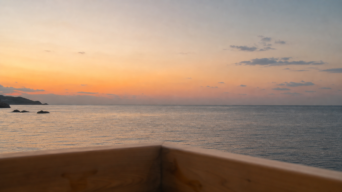湯船の縁越しに見える海と夕景
