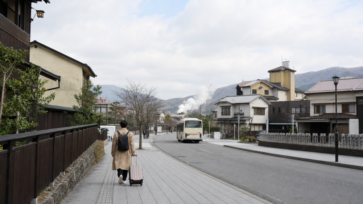 温泉街を歩く旅行者と遠くの路線バスを組み合わせた車なし旅行のイメージ
