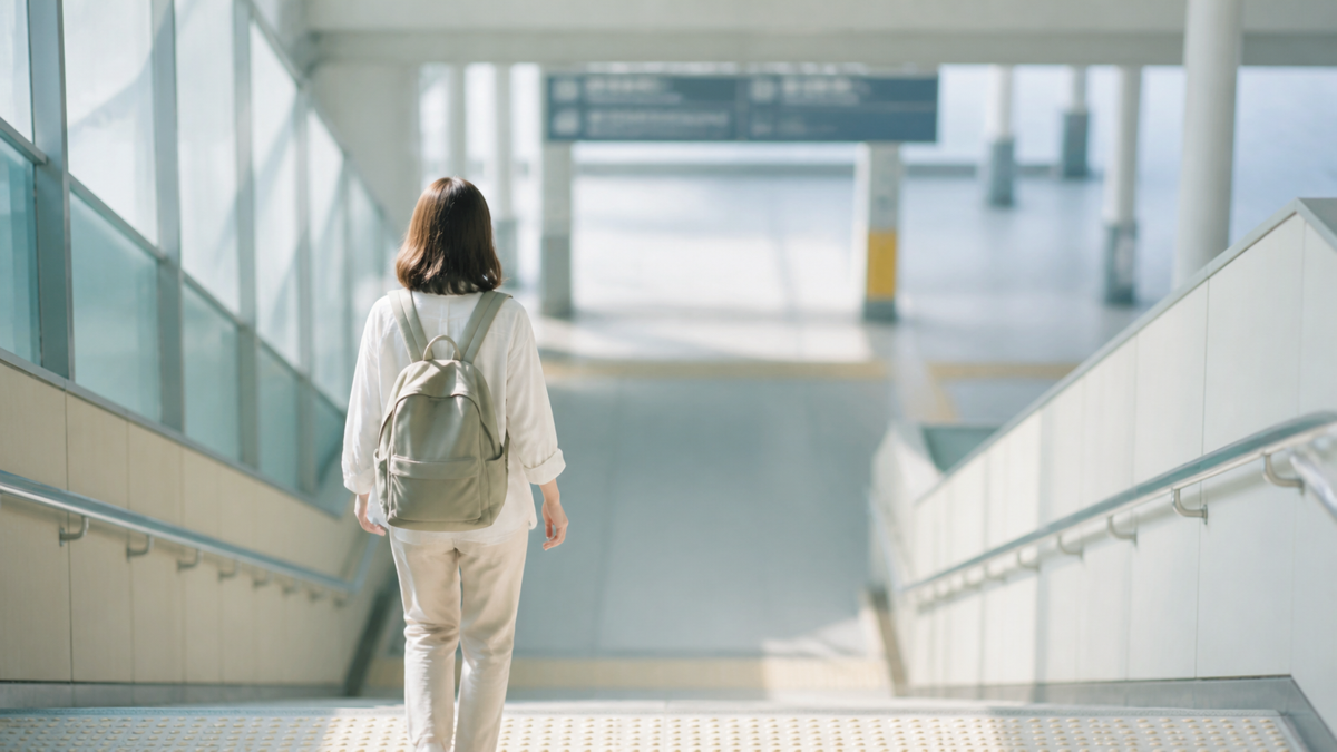 両手を空けてリュックで駅の階段を移動する旅行者
